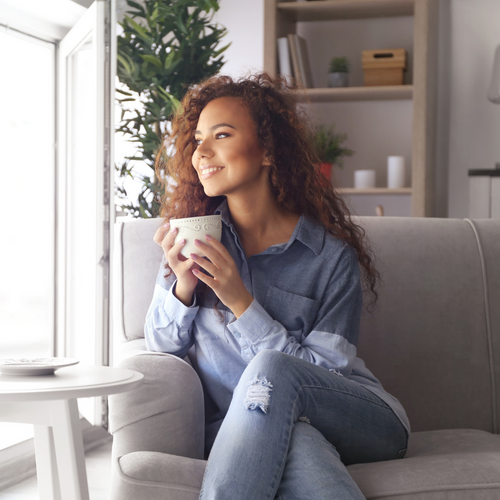1 happy woman drinking coffee sitting on couch